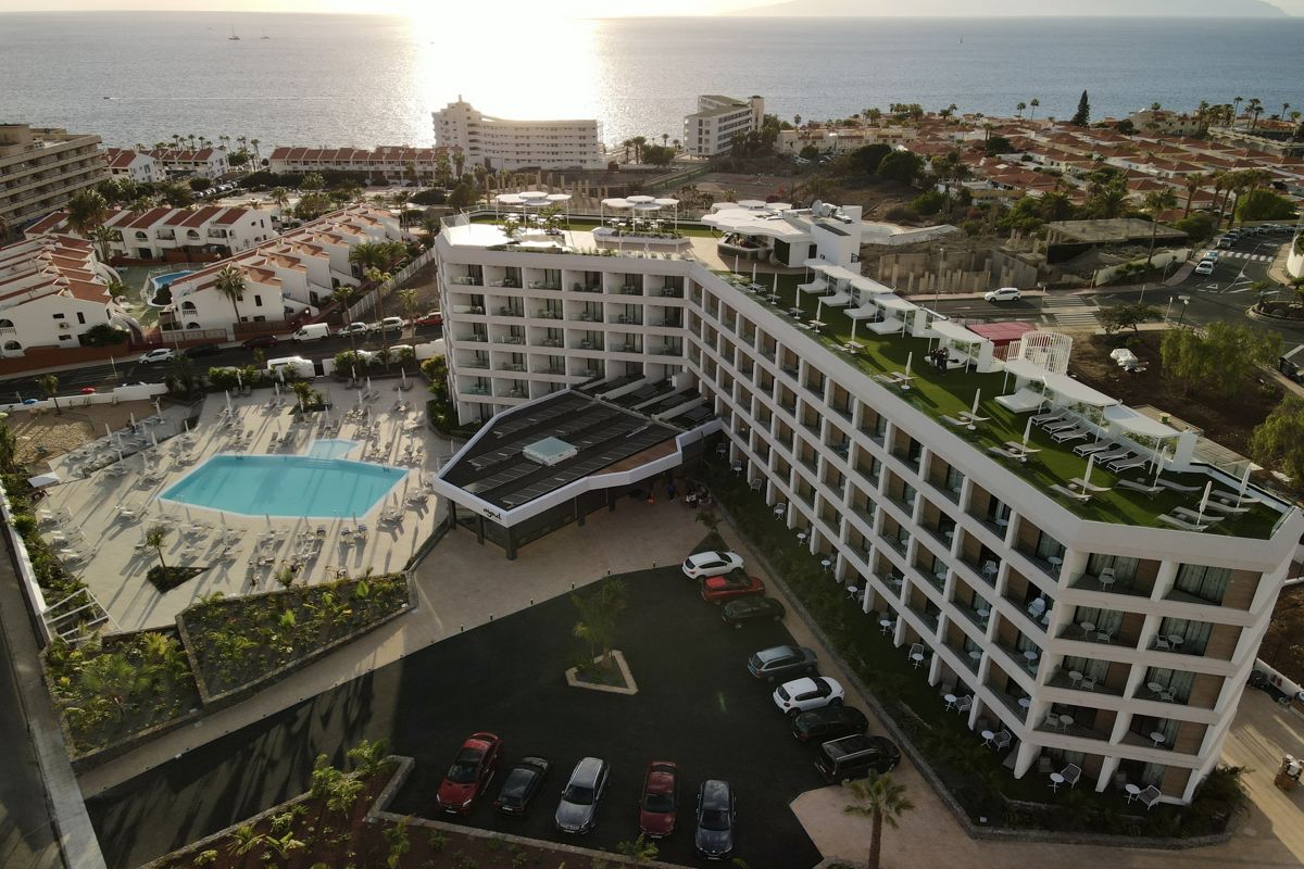 Hotel mit Pool und Parkplatz in Tenerife mit Blick auf das Meer im Hintergrund.