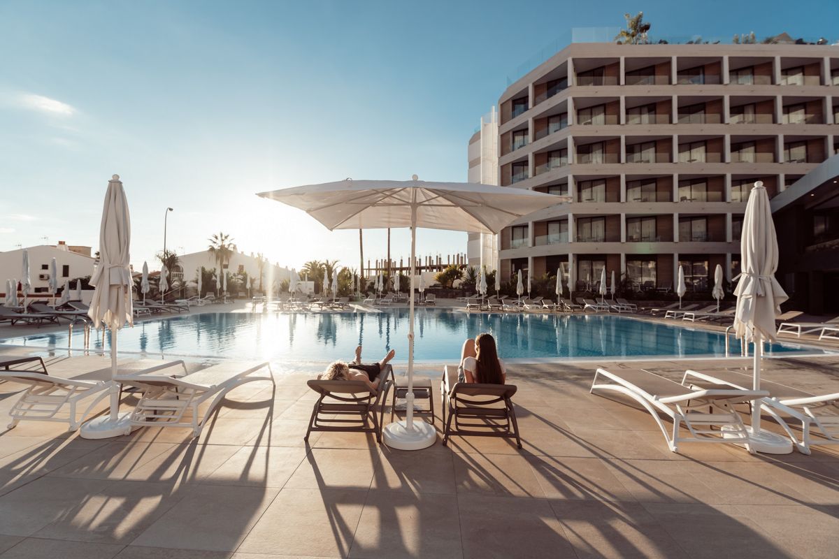 Zwei Personen entspannen auf Liegestühlen am Pool des Hotels in Teneriffa.