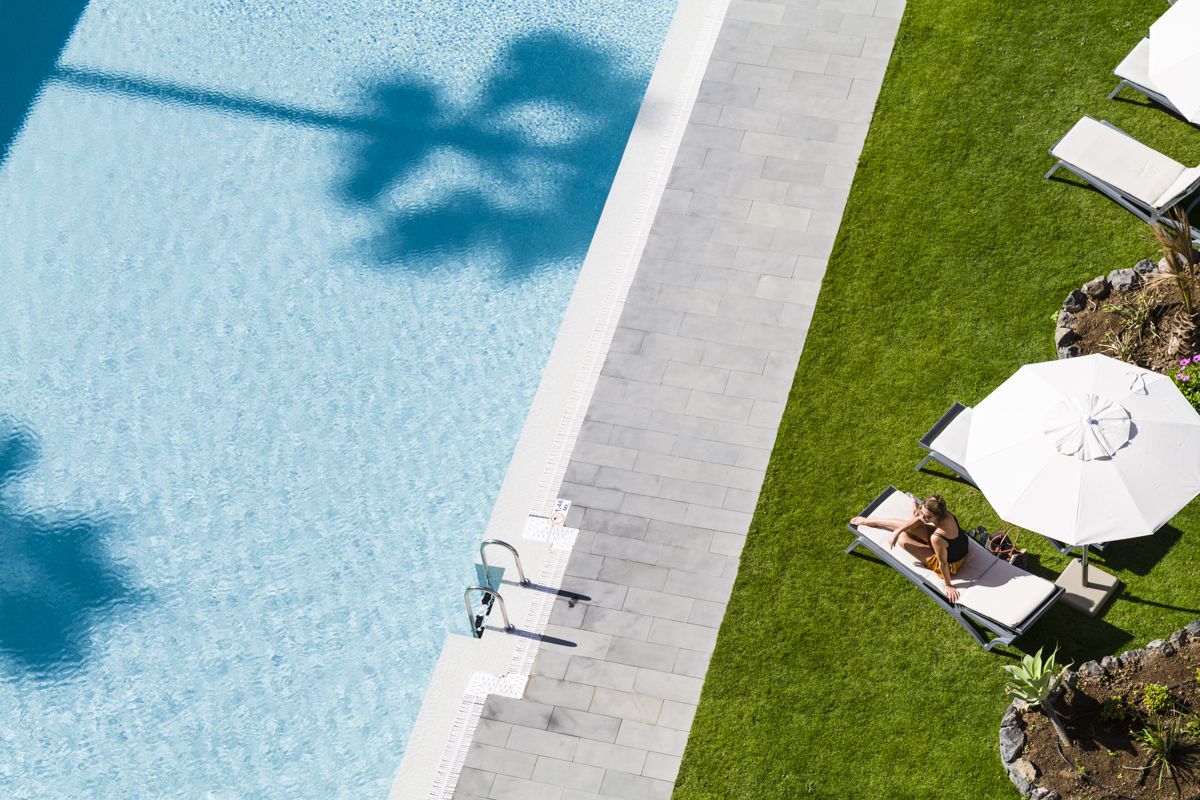 Person auf einer Sonnenliege neben einem Pool in einem Hotel in Tenerife.