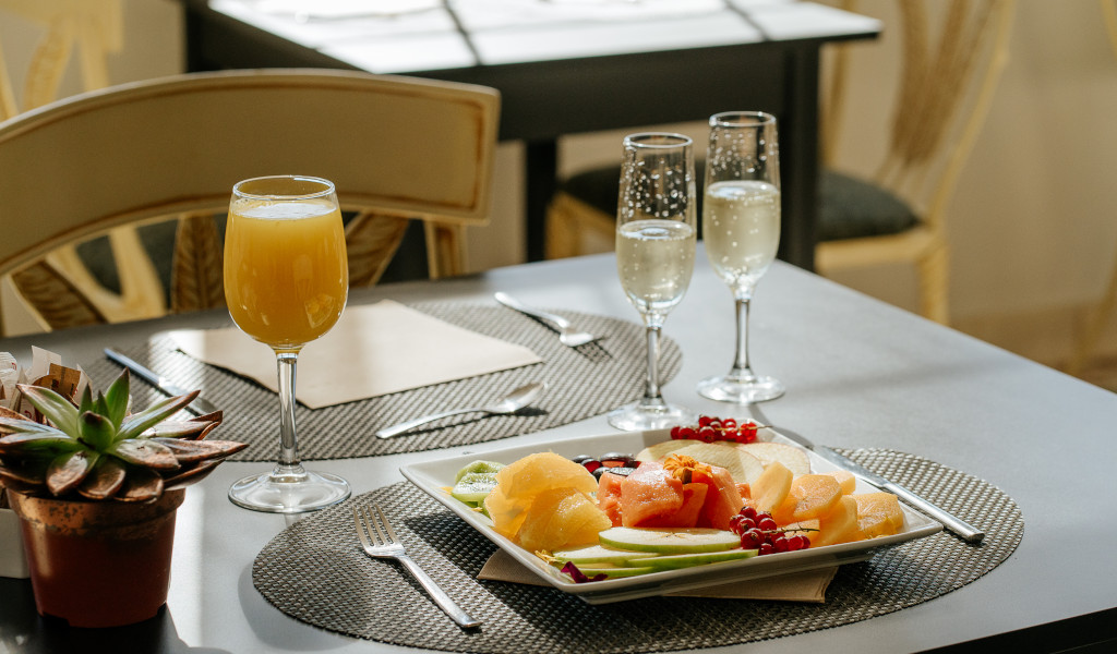 Frühstückstisch mit Saft, Sektgläsern und Obstteller in einem Café in Teneriffa.
