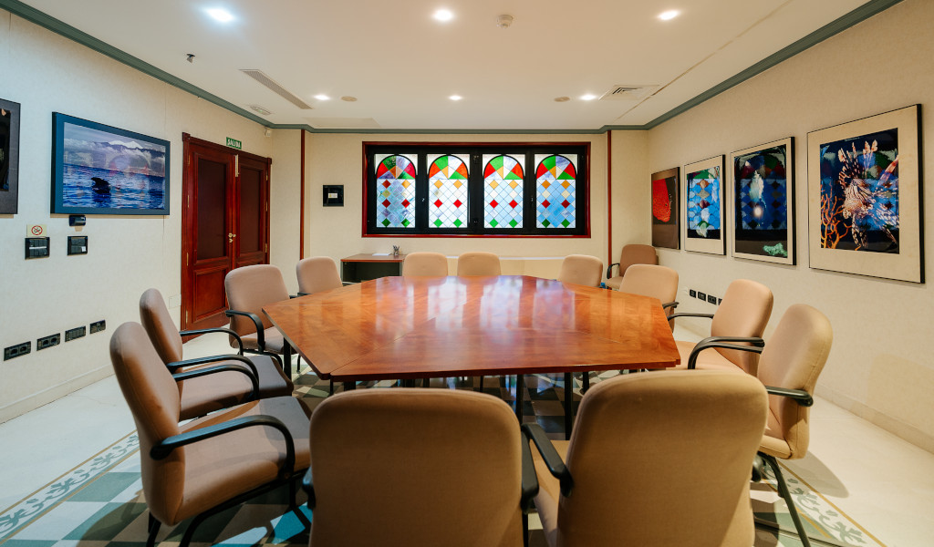 Konferenzraum in Tenerife mit achteckigem Tisch und zehn Stühlen. Fenster mit buntem Glasfenster.