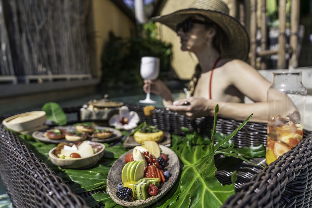 Frühstücksplatte mit Früchten und Getränken, Frau im Hintergrund am Pool in Tenerife.