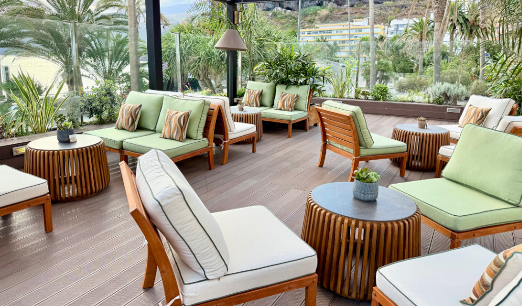 Terrasse mit grünen Sofas und Holzmöbeln, umgeben von Pflanzen in Tenerife.