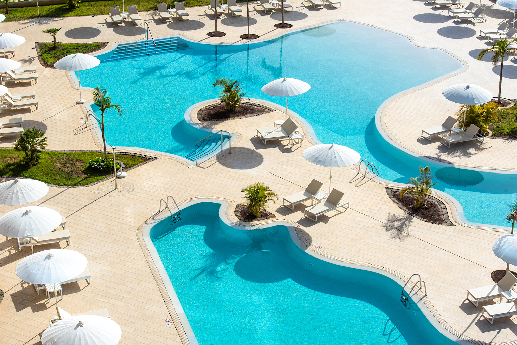 Außenpoolbereich mit Liegestühlen und Sonnenschirmen in einem Resort auf Teneriffa.