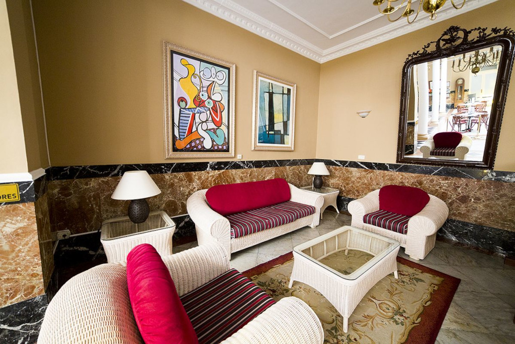 Sitzecke in einem Hotel in Tenerife mit roten Kissen, zwei Gemälden und großem Spiegel.