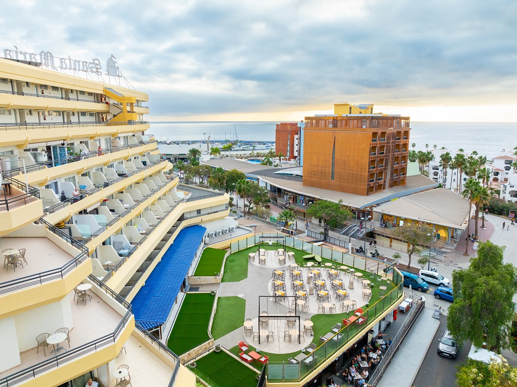 Hotel mit Balkonen und Außenbereich mit Tischen in Los Cristianos, Teneriffa.