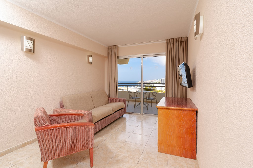 Wohnzimmer mit Sofa, Fernseher und Balkon mit Blick auf das Meer in Teneriffa.