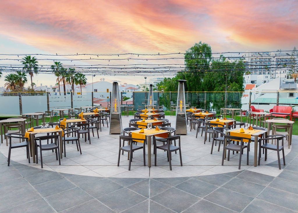 Außenbereich eines Restaurants in Teneriffa mit gedeckten Tischen bei Sonnenuntergang.