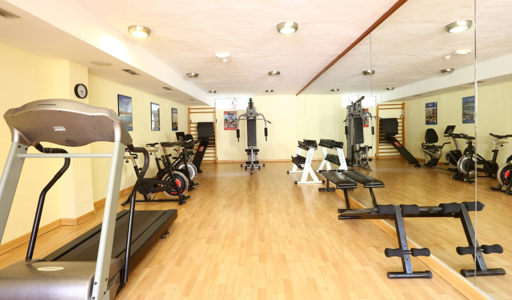 Fitnessraum mit Laufband, Hanteln und Fitnessgeräten in einem Hotel in Tenerife.