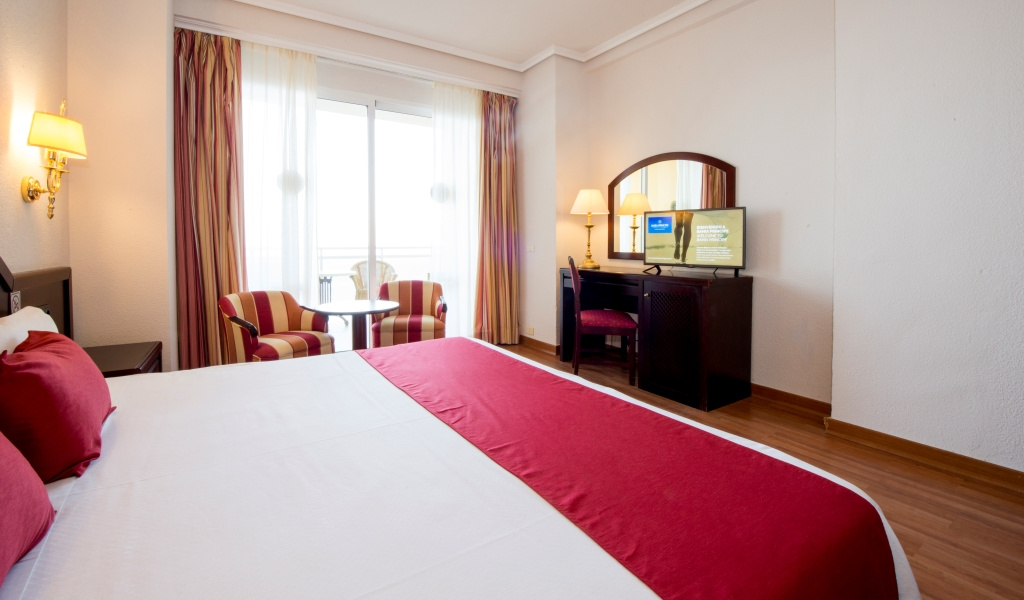 Hotelzimmer im Puerto de la Cruz mit Doppelbett, Fernseher und Balkon im Hintergrund.