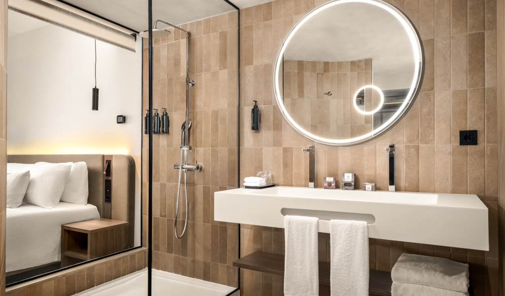 Moderne Hotelbadezimmer mit Dusche, Rundspiegel und Waschbecken in Teneriffa.