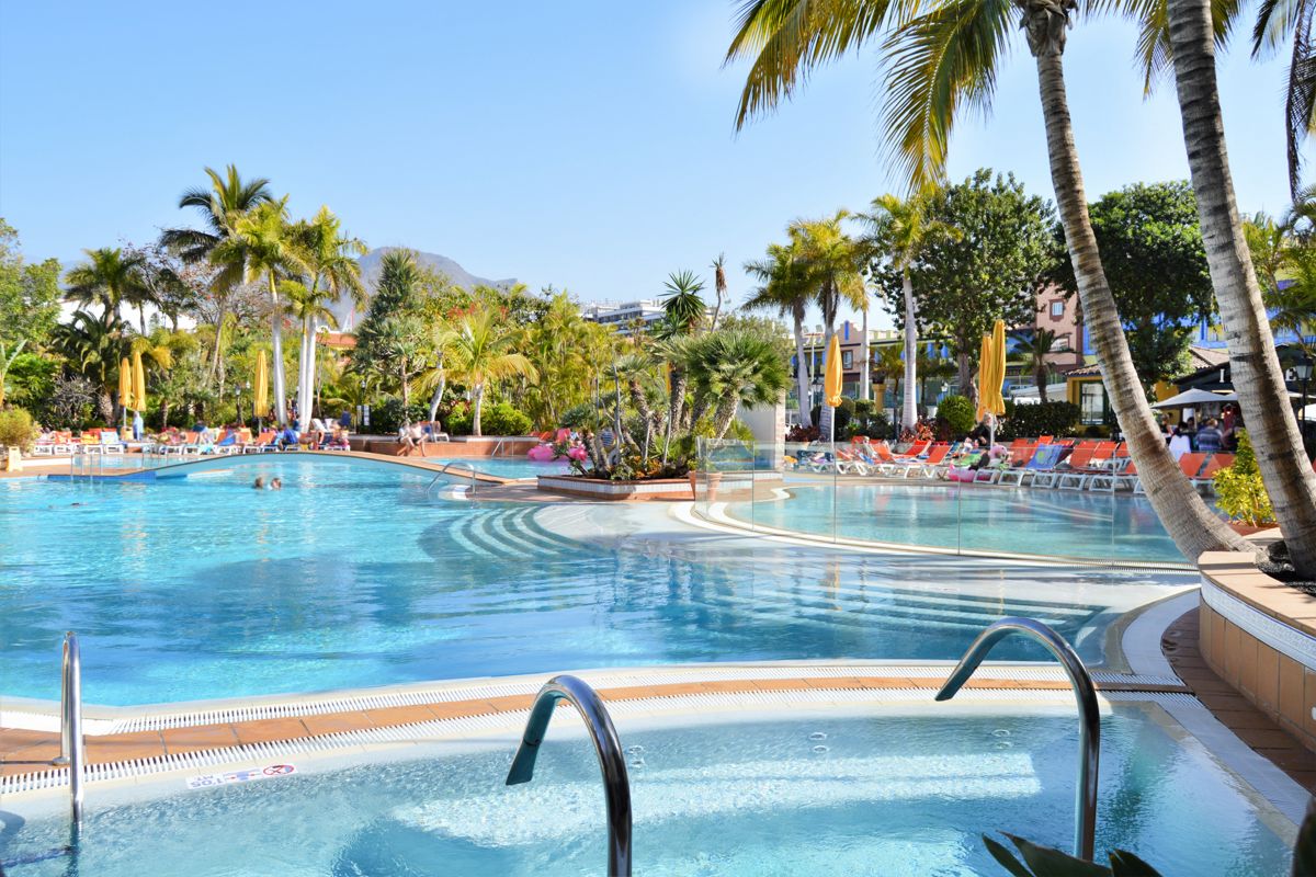 Schwimmbad mit Palmen und Sonnenliegen im Hotel in Costa Adeje, Teneriffa.