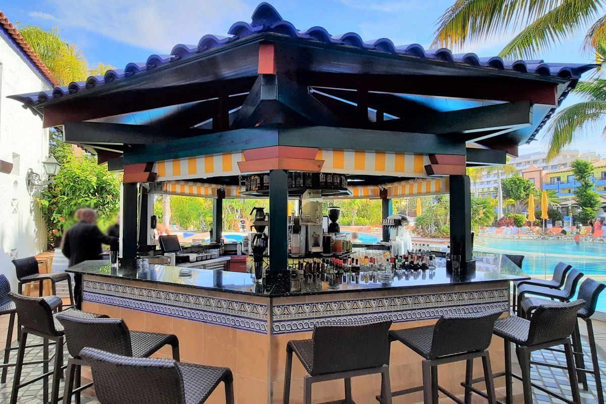 Poolbar in einem Resort in Puerto de la Cruz, umgeben von Palmen und Liegestühlen.