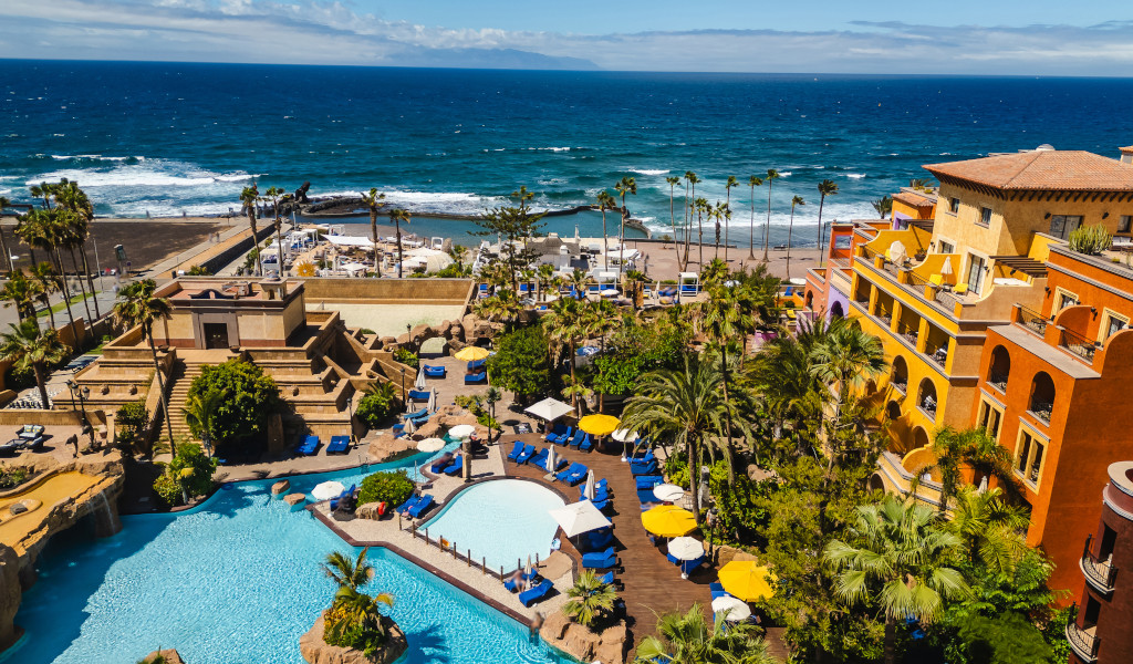 Poolbereich mit Palmen am Strand in Adeje, Teneriffa, mit Blick aufs Meer.