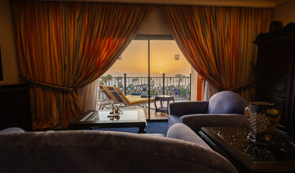 Sofa und Vorhänge mit Blick auf Sonnenuntergang in Teneriffa über Balkon.