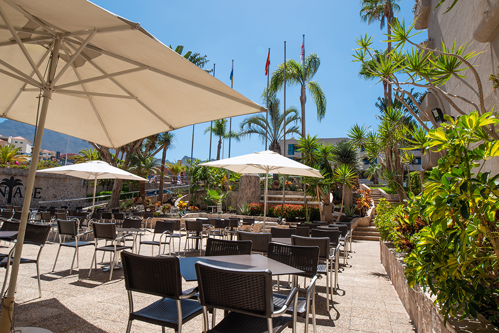 Außenterrasse mit Tischen und Sonnenschirmen in Adeje, Teneriffa.