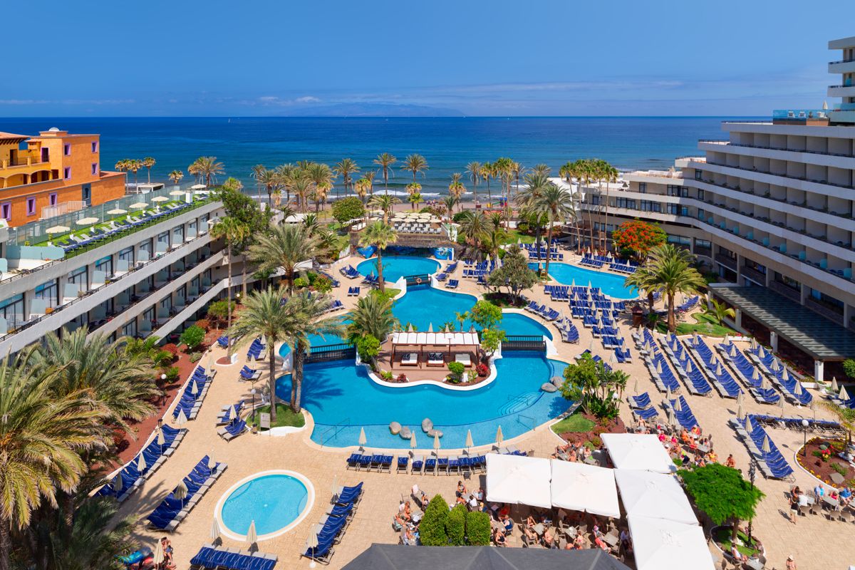Poolbereich eines Resorts mit Blick auf das Meer in Playa de las Américas, Teneriffa.