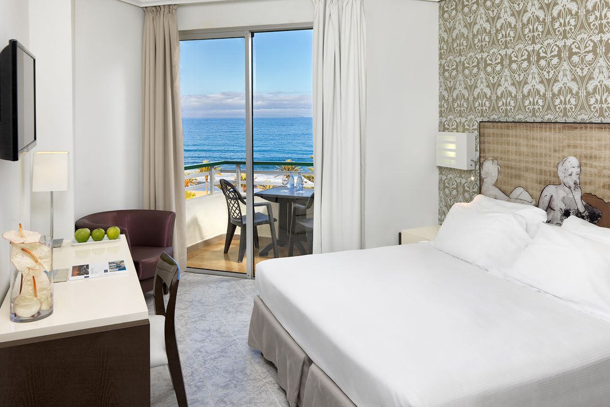 Zimmer mit Blick aufs Meer in Tenerife, Tisch mit Flaschen und Stühlen auf dem Balkon.