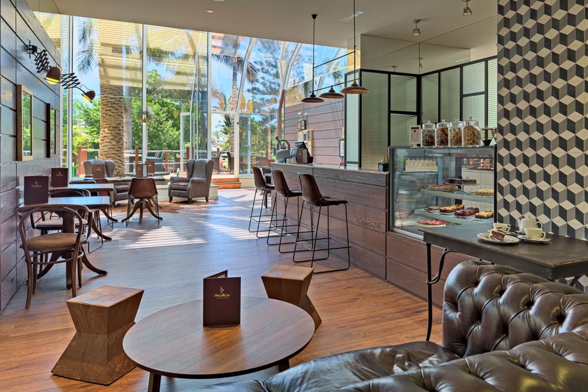 Café in Puerto de la Cruz mit großen Fenstern, Tischen und einer Theke mit Gebäck.