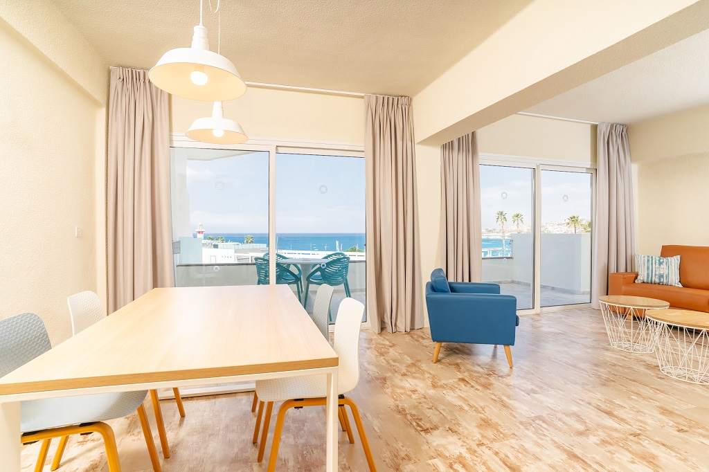Esszimmer mit Tisch, Stühlen, Sofa, Blick auf Meer und Palmen in Teneriffa.
