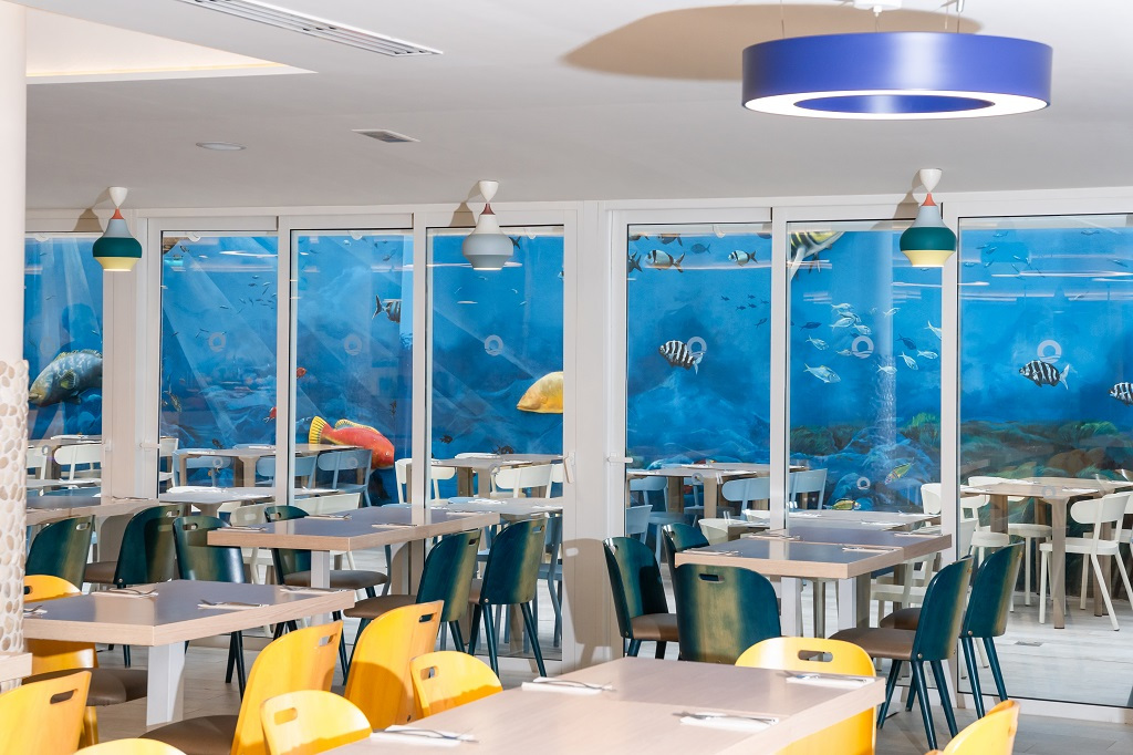 Restaurantbereich mit bunten Stühlen und Wandbemalung mit Fischen in Puerto de la Cruz, Teneriffa.
