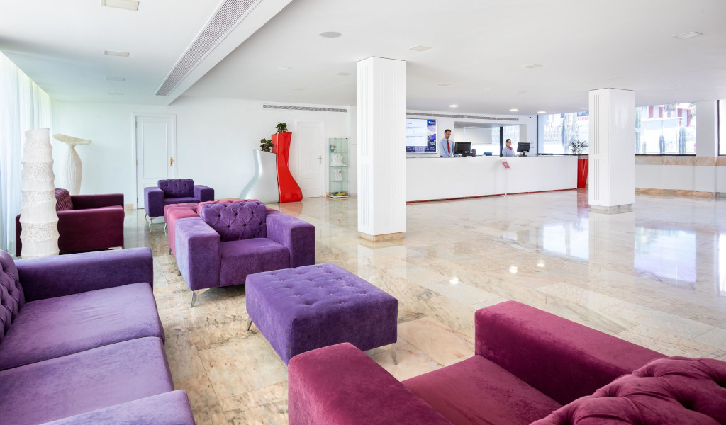 Empfangsbereich mit lila Sofas und Rezeption in einem Hotel in Tenerife.