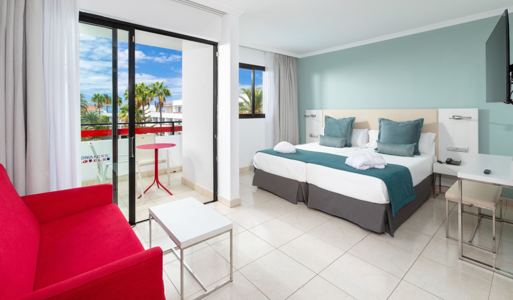 Modernes Hotelzimmer in Tenerife mit Doppelbett und Blick auf Palmen.
