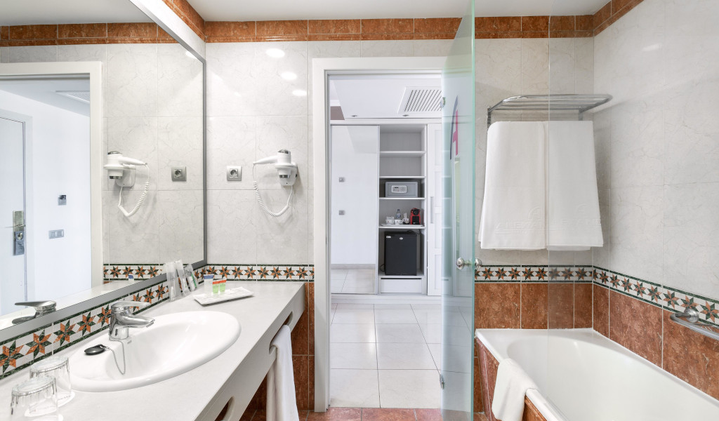Badezimmer mit Waschbecken, Spiegel, Haartrockner und Badewanne in einem Hotel in Tenerife.