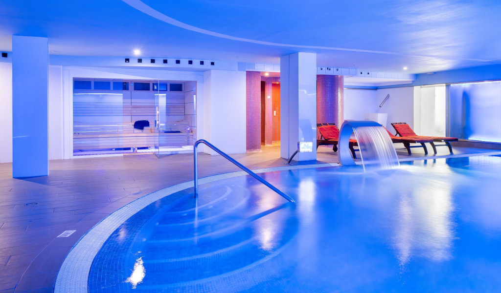 Innenpool mit Liegestühlen und Wasserfall im Spa-Bereich von Adeje, Teneriffa.