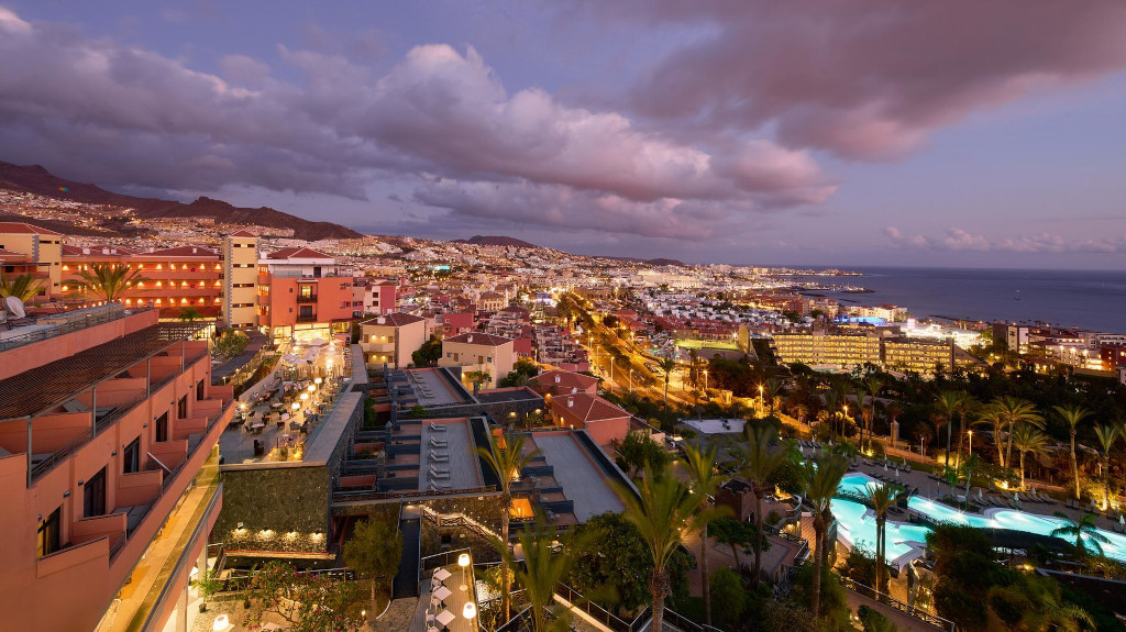 Stadtansicht von Adeje bei Dämmerung mit Lichtern und Meerblick auf Teneriffa.