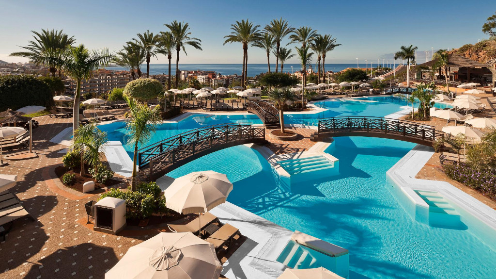 Poollandschaft mit Palmen und Liegestühlen im Hotel in Teneriffa.