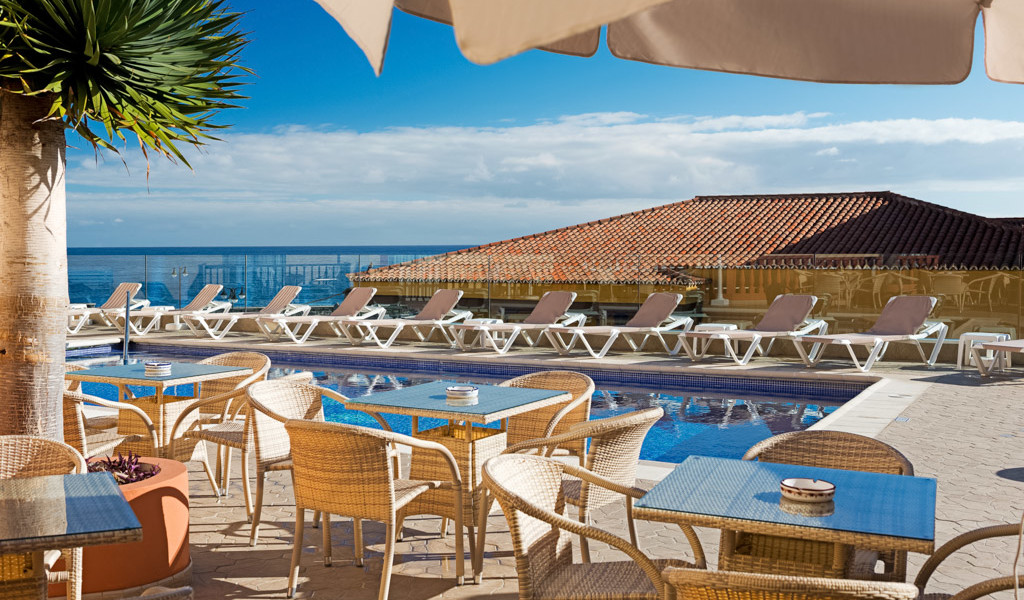 Sonnenterrasse mit Pool und Liegestühlen am Meer in Puerto de la Cruz auf Teneriffa.