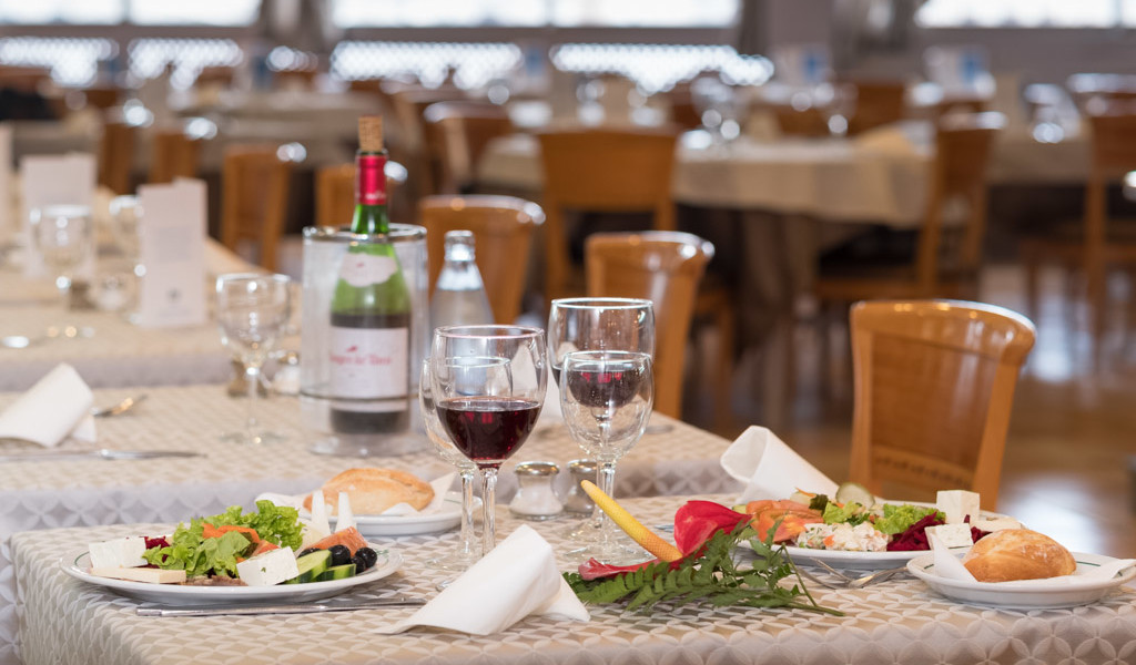 Tisch im Restaurant mit Salat, Brot und Rotwein. Im Hintergrund leere Tische in Tenerife.