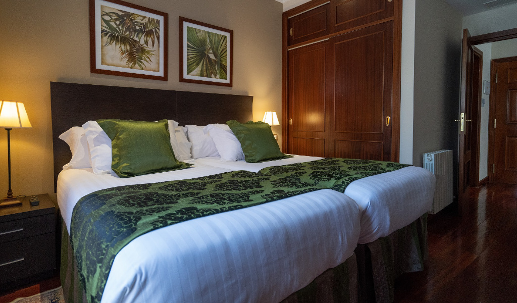 Zwei Betten mit grünen Kissen in einem Hotelzimmer in Tenerife.