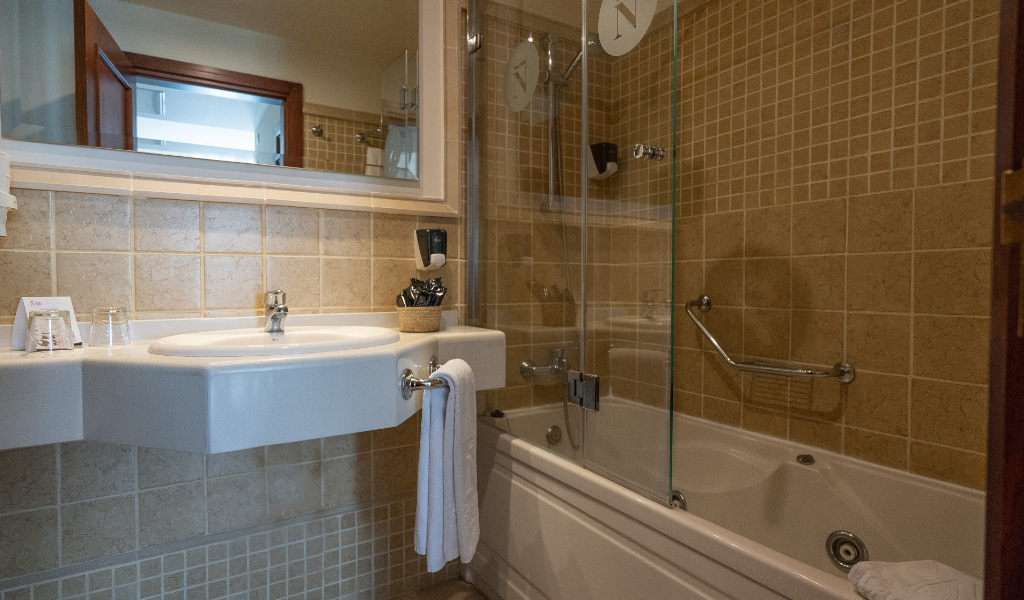 Badezimmer in einem Hotel in Puerto de la Cruz mit Spiegel, Waschbecken und Badewanne.