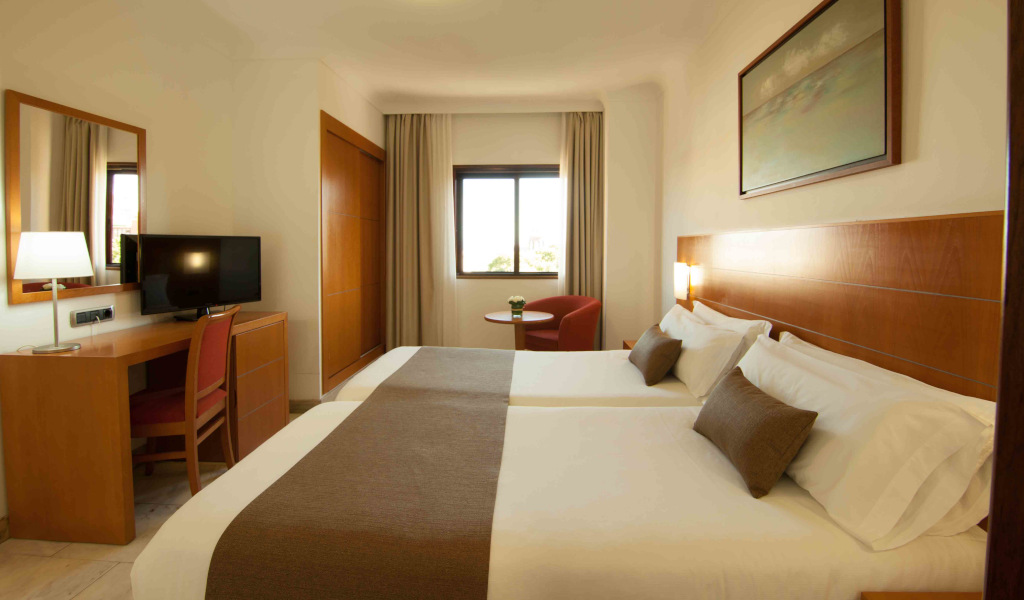 Zwei Betten in Hotelzimmer in Teneriffa mit Schreibtisch und Fernseher.