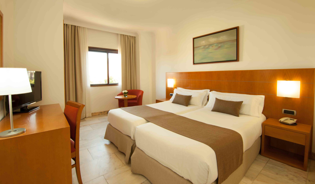 Zweibettzimmer mit Schreibtisch und Fenster im Hotel in Teneriffa.