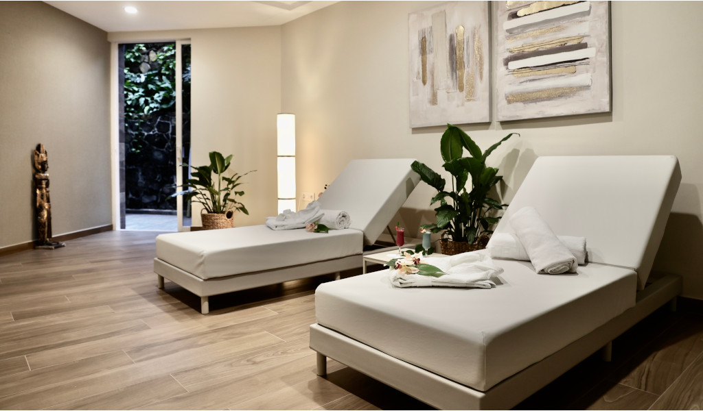 Zwei Liegen mit Handtüchern, Pflanzen und Kunstwerken im Wellnessraum in Tenerife.