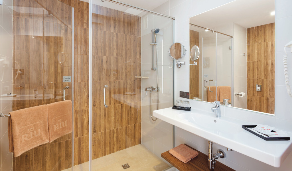 Hotelbadezimmer auf Teneriffa mit Dusche und Waschbecken. Handtücher der Marke Riu hängen bereit.