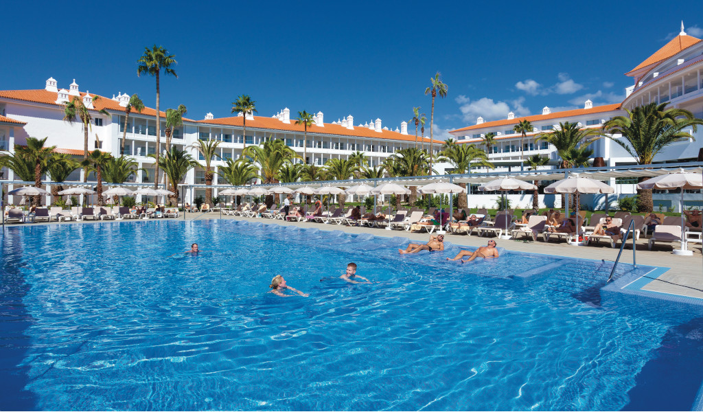 Freibad mit schwimmenden Menschen vor einem Hotel auf Teneriffa.