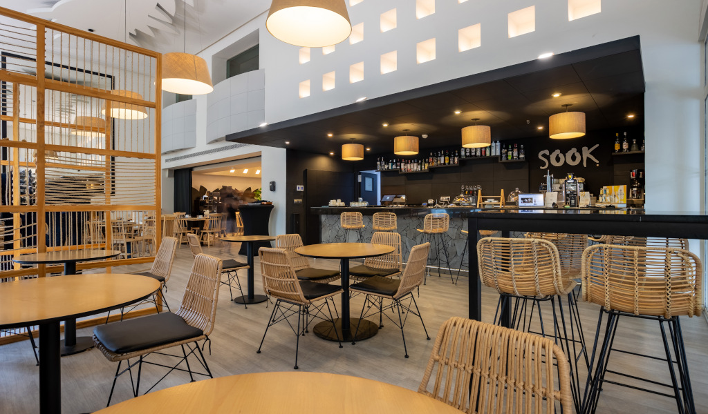 Sitzecke im Café Sook in Teneriffa mit Holztischen und geflochtenen Stühlen.