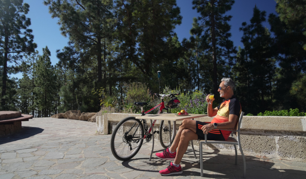Mann trinkt Saft neben Fahrrad auf Waldweg in Tenerife.