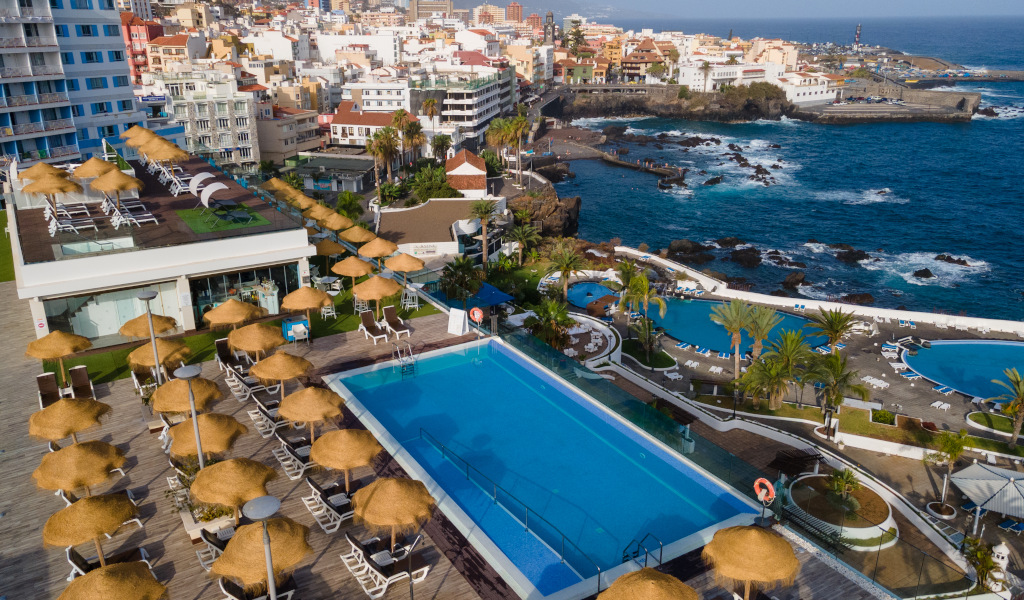Hotelpool mit Sonnenliegen am Meer in Puerto de la Cruz, Teneriffa.