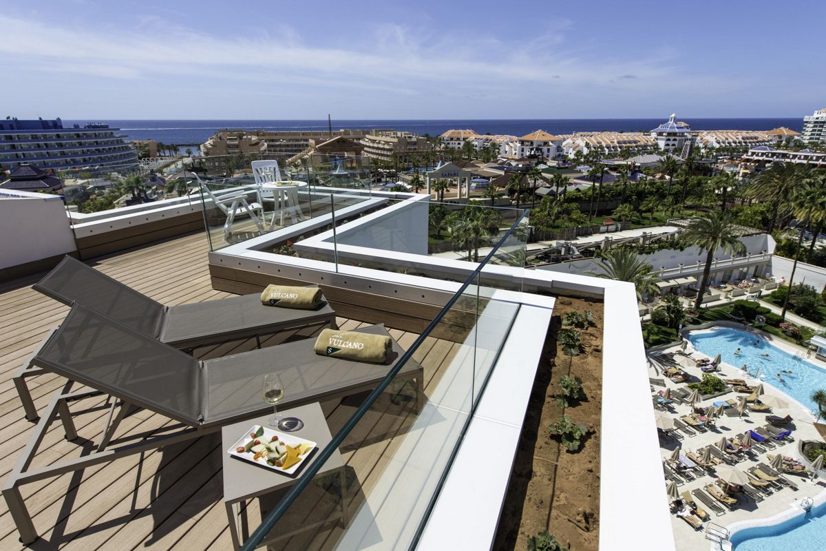 Sonnenterrasse mit Blick auf Costa Adeje, Liegestühle, Tisch mit Snacks und Pool.