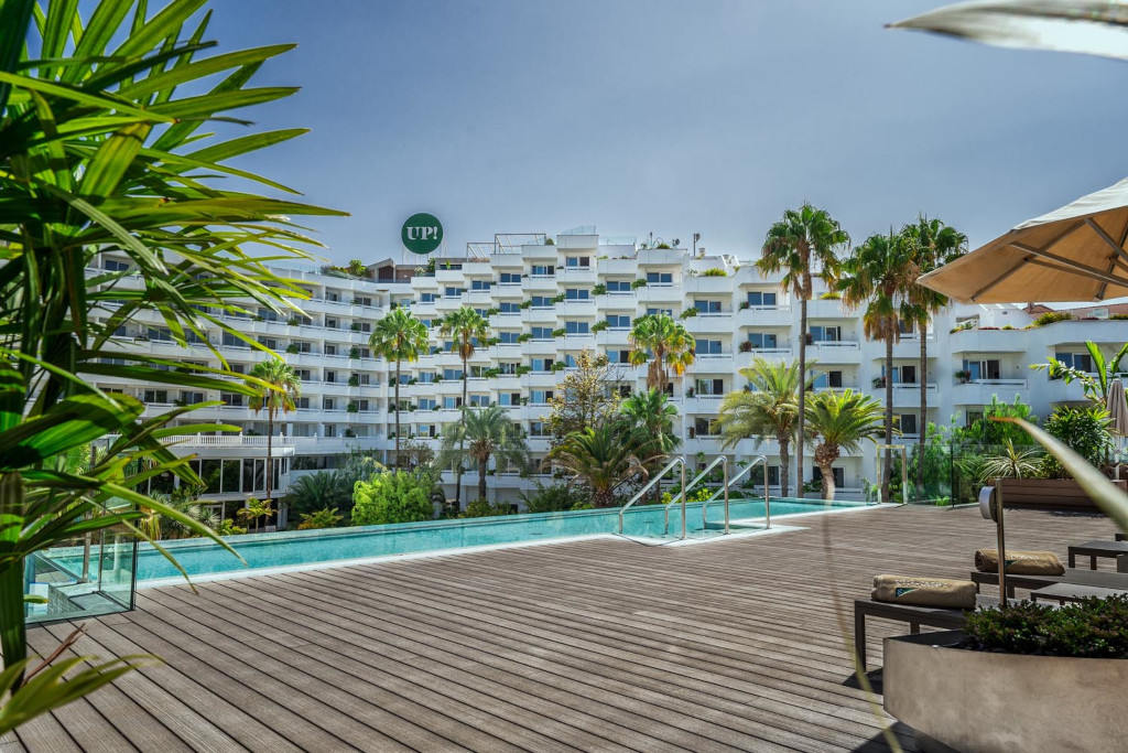 Poolbereich mit Palmen und Hotelgebäude in Playa de las Américas, Teneriffa.
