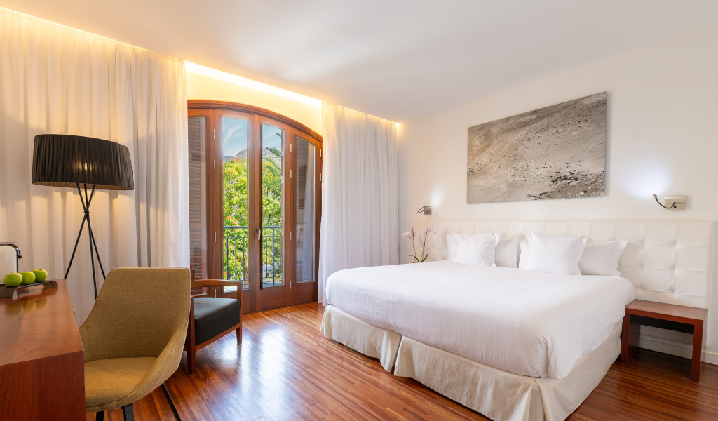 Moderne Hotelzimmeransicht mit großem Bett, Schreibtisch und Balkonblick in Puerto de la Cruz.