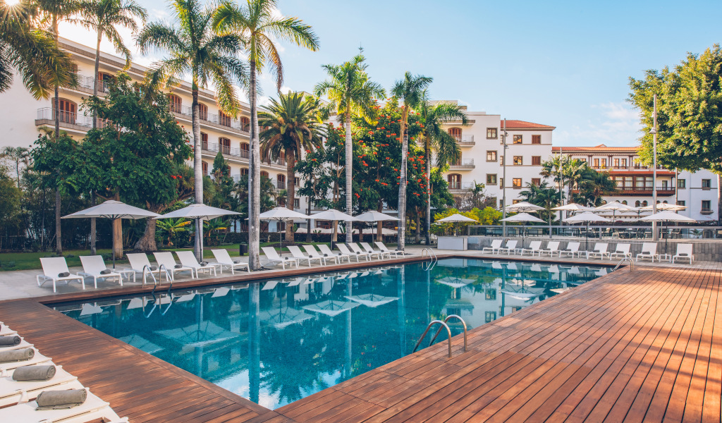 Außenpool mit Liegestühlen und Palmen in Puerto de la Cruz, Teneriffa.