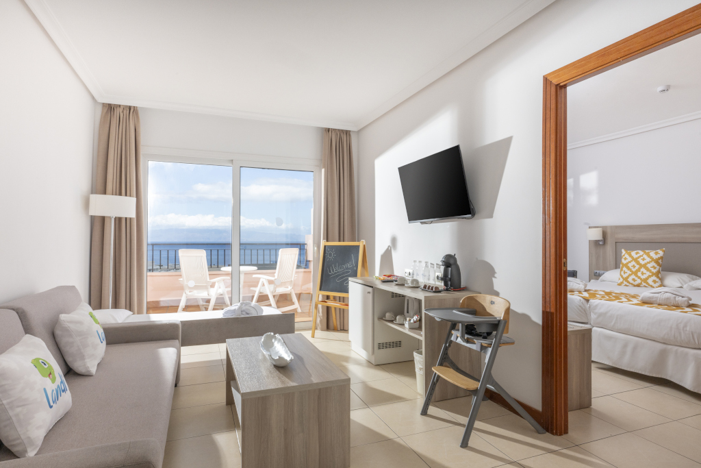 Wohnzimmer mit Sofa, Tisch, Fernseher, Balkon mit Meerblick und Zugang zum Schlafzimmer in Tenerife.