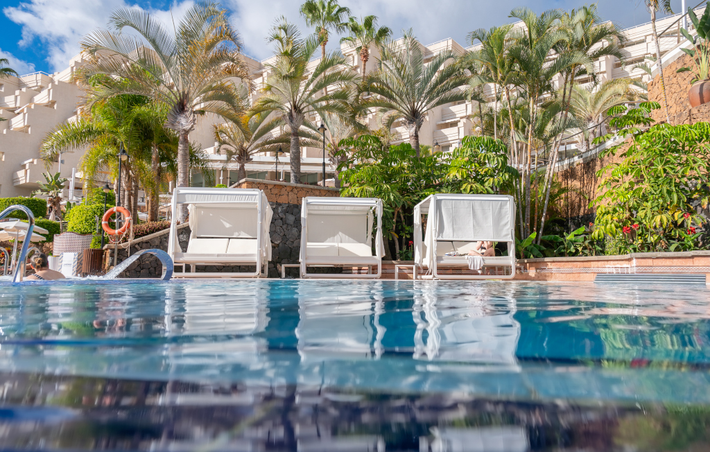 Sonnenliegen und Palmen am Pool in Hotel in Costa Adeje, Teneriffa.