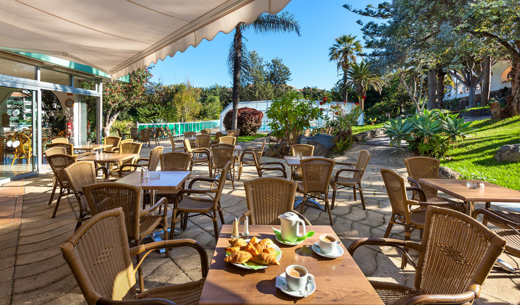 Terrasse eines Cafés in Puerto de la Cruz, mit Tischen und Stühlen im Freien.